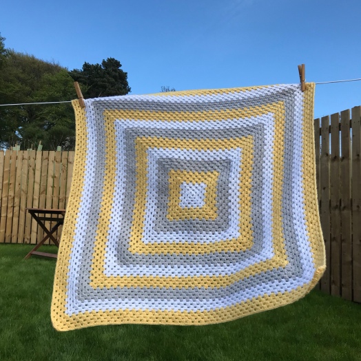 Crochet baby blanket in yellow white and grey